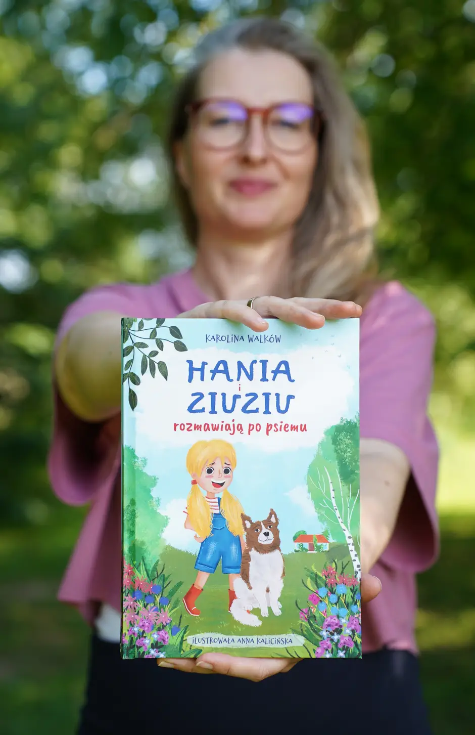 Karolina Walków trzyma książkę Hania i Ziuziu rozmawiają po psiemu